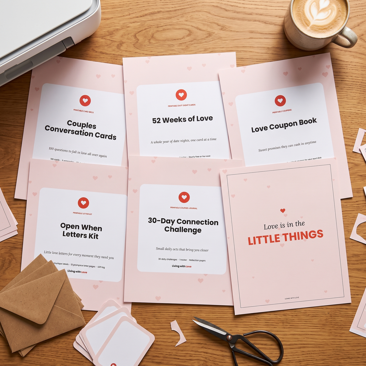 All six printed Love Kit covers laid out on a desk with scissors and a latte